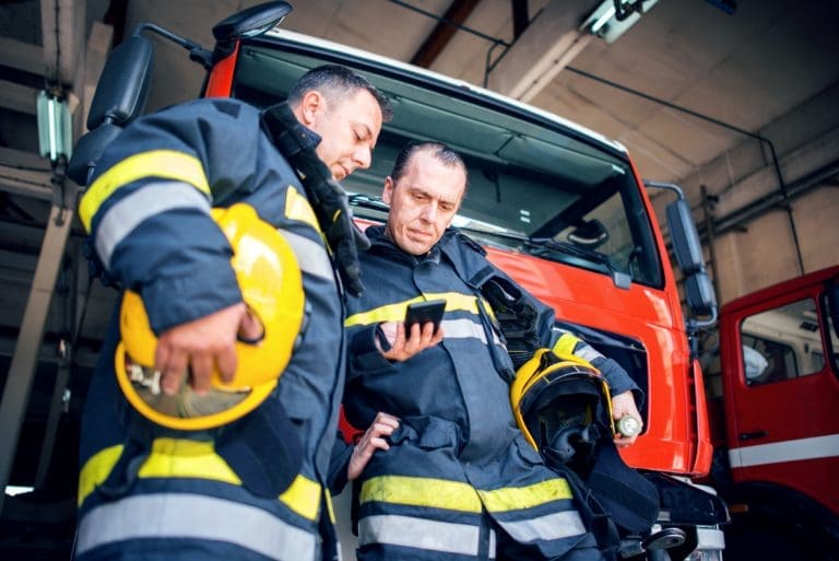 Two firefighters looking at a phone.